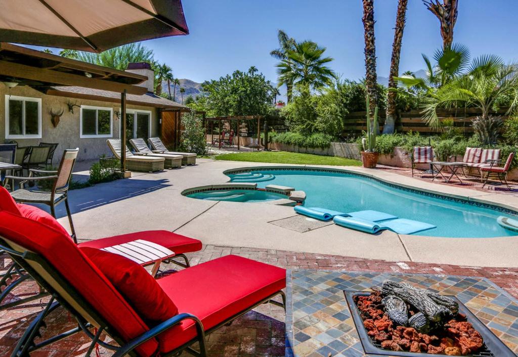 a swimming pool with red chairs and a fire pit at Serenity Palm Springs Ranch Permit# 2869 in Palm Springs