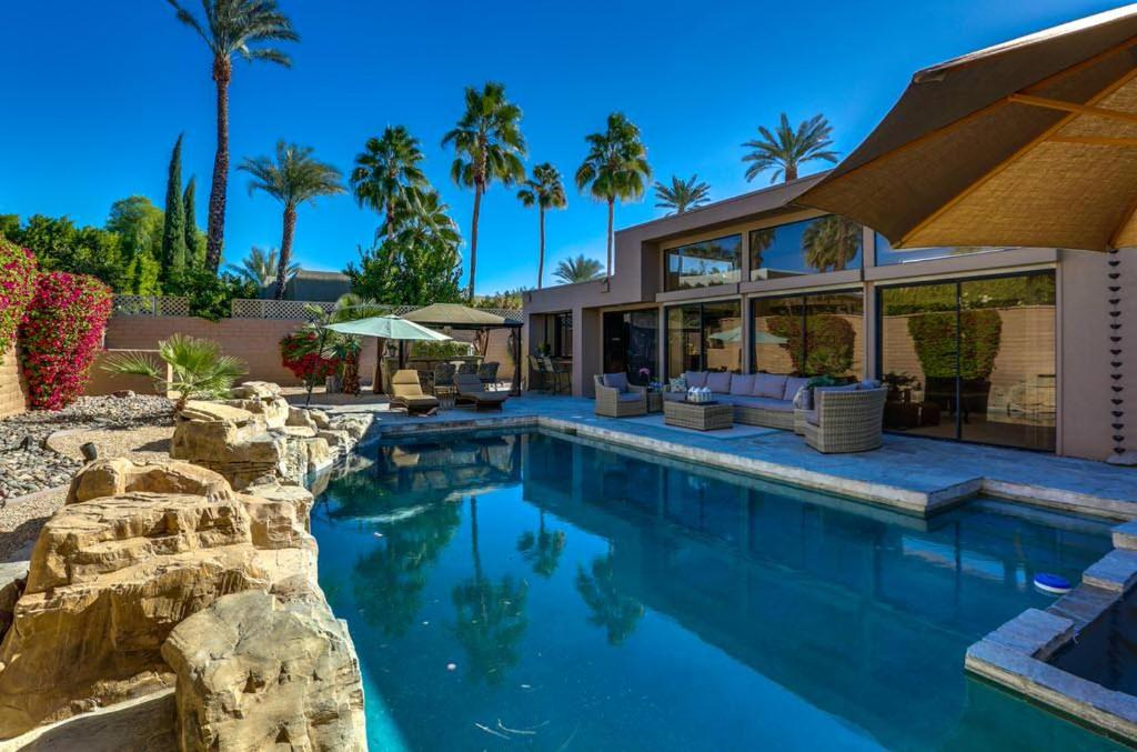 a swimming pool with a house and palm trees at Rancho Mirage Tamarisk Villa in Rancho Mirage