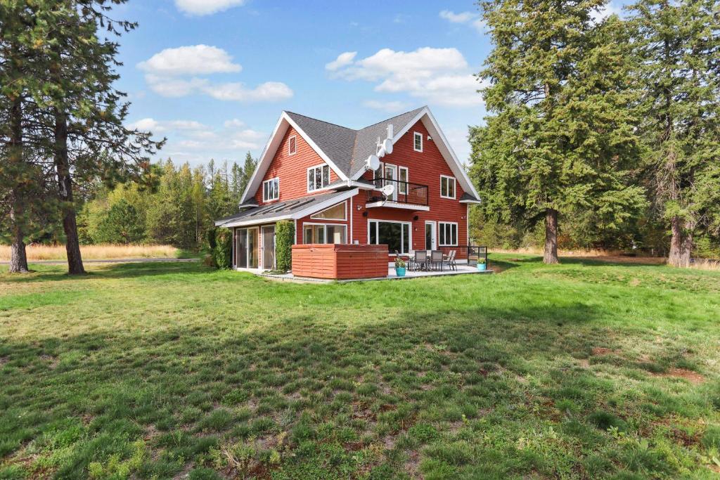 une grande maison rouge avec une grande cour dans l'établissement Lakeview Home with new hot tub - Sleeps 10, à Sandpoint