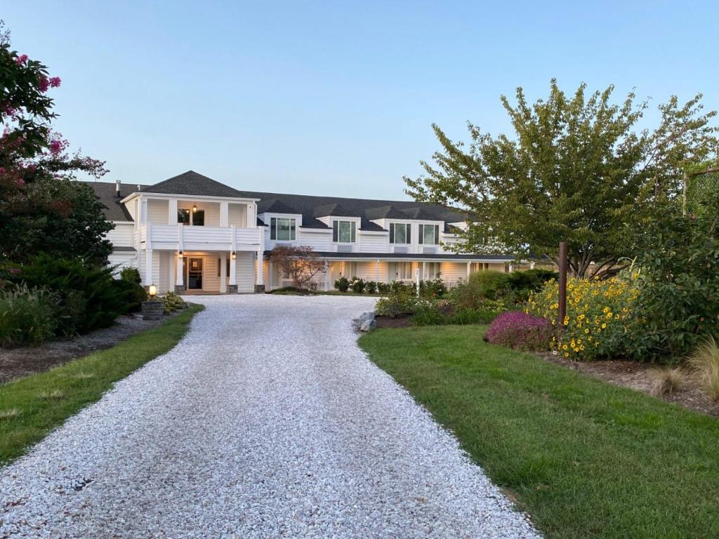 une grande maison blanche avec une allée en gravier dans l'établissement Tilghman Island Inn, à Tilghman Island