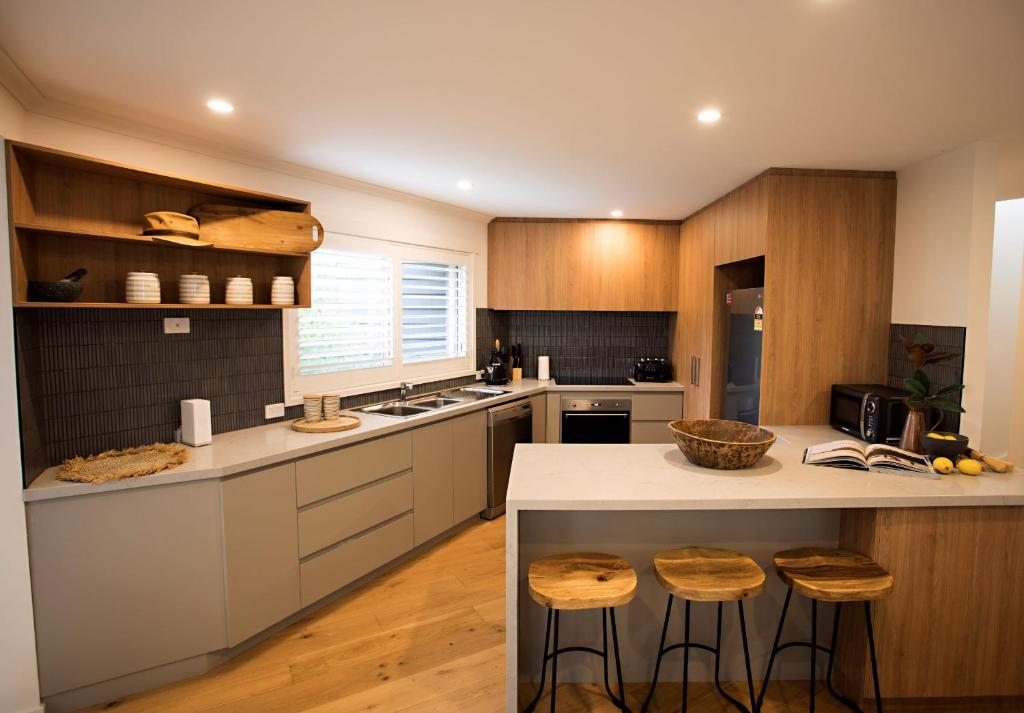 a kitchen with wooden cabinets and a counter with stools at MONREPOS in Point Lonsdale