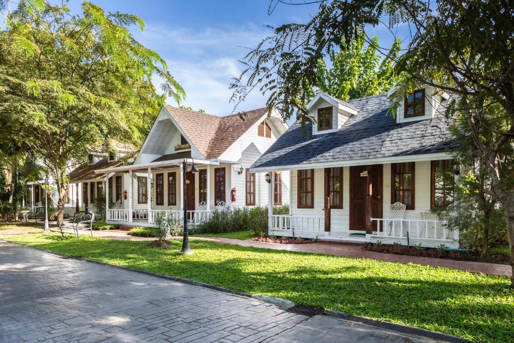 une maison blanche avec un toit en gambrel dans l'établissement Sakarin Valley Resort, à Kanchanaburi