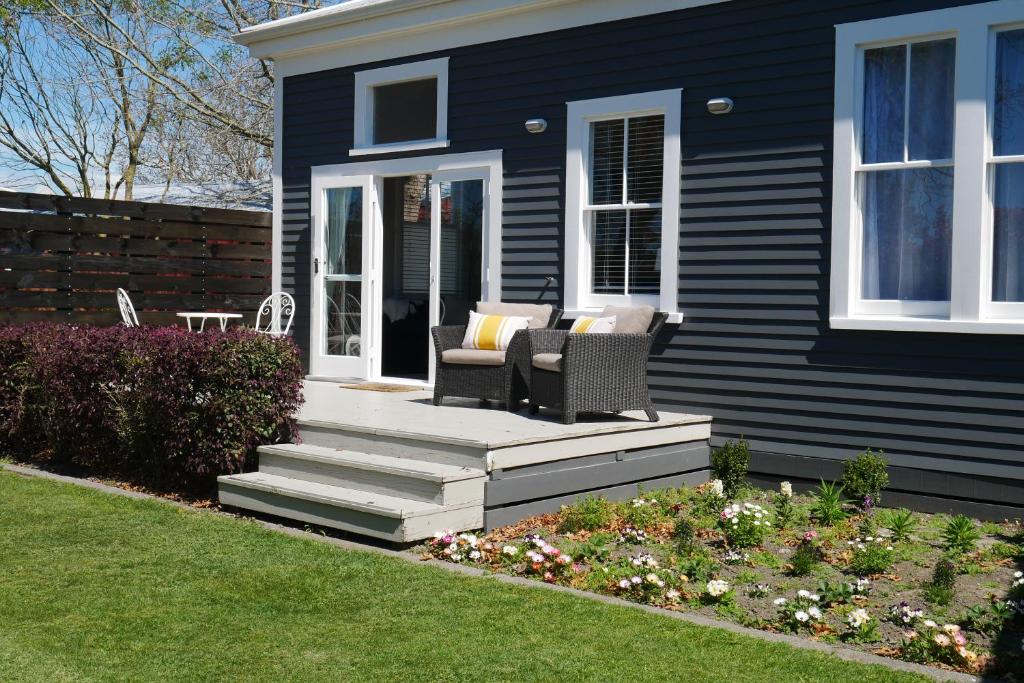 une maison noire avec 2 chaises sur la terrasse couverte dans l'établissement Havelock Cottage on St Georges, à Havelock North