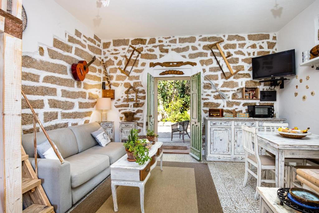 a living room with a couch and a stone wall at Tipica casa a San Pantaleo in San Pantaleo
