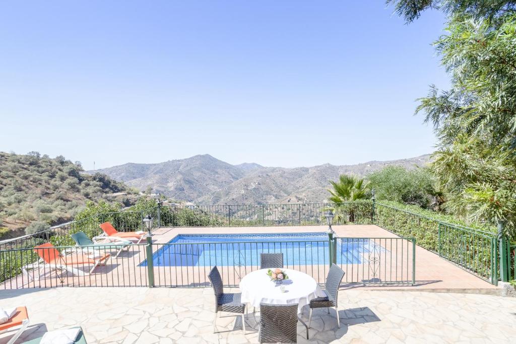 une terrasse avec une table, des chaises et une piscine dans l'établissement Casa las Olivas, à Sayalonga