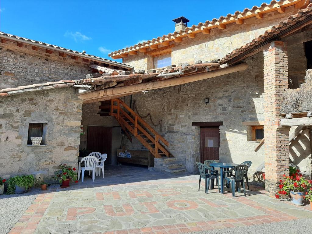 een patio met een tafel en stoelen in een stenen gebouw bij Casa Rural Más Pujol in Campdevánol