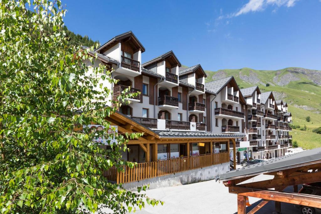 a large building with mountains in the background at Résidence Odalys L'Ouillon in Saint-Sorlin-dʼArves