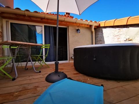 an umbrella sitting on a deck with a table and a table at Maison Small Luxury ( planxa,suite,solarium,jacuzzi,pas de vis à vis) in Argelès-sur-Mer
