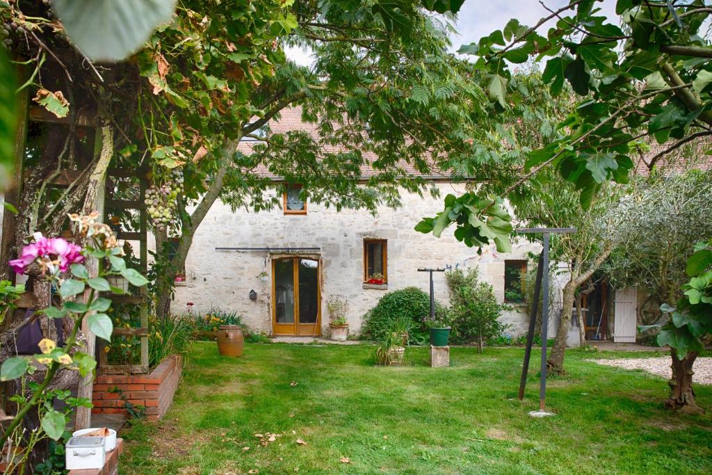 una casa de ladrillo blanco con una puerta amarilla en un patio en LA FERME DES NONAINS en Montjavoult