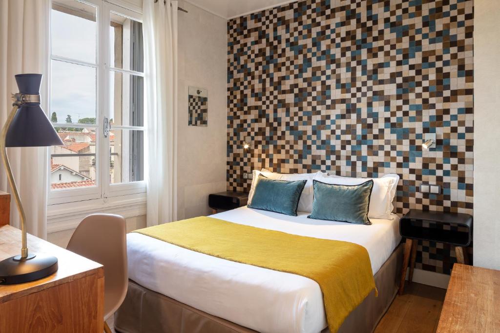 Un dormitorio con una cama grande y una ventana en Hotel des Arceaux, en Montpellier