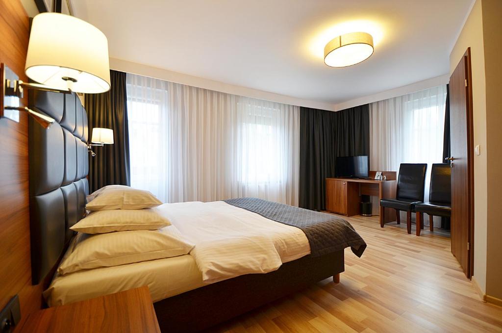 a hotel room with a bed and a desk and chairs at Villa Grace - wypoczynek bez dzieci in Szklarska Poręba
