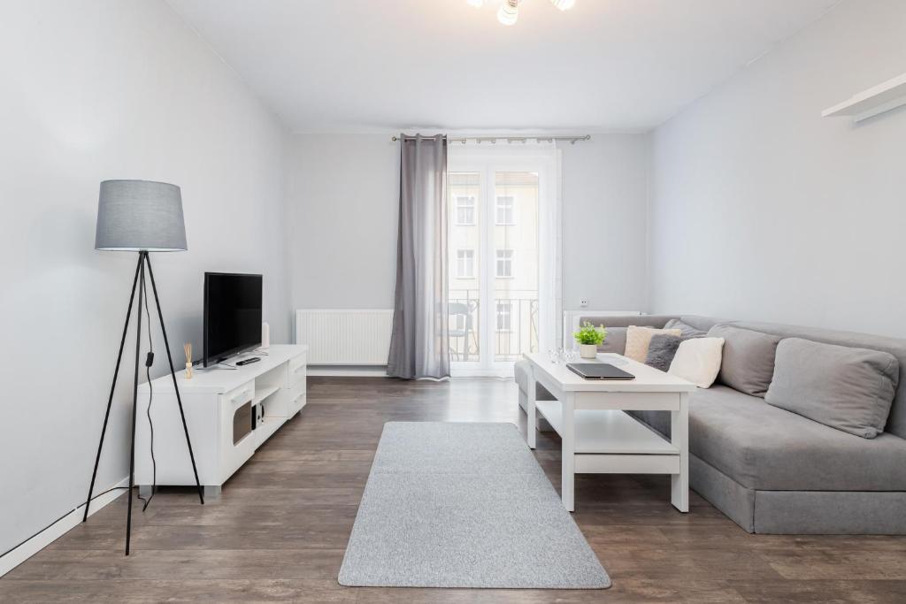 uma sala de estar com um sofá e uma mesa em Apartments Dworcowa by Renters em Kolobrzeg