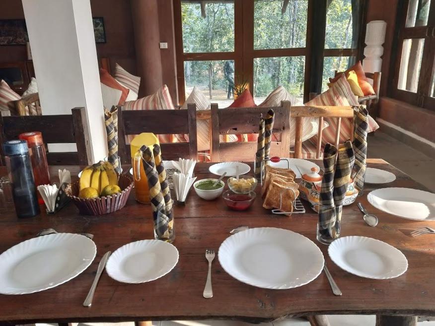 una mesa de madera con platos blancos y cucharas en ella en Emerald Tiger Retreat, en Tāla