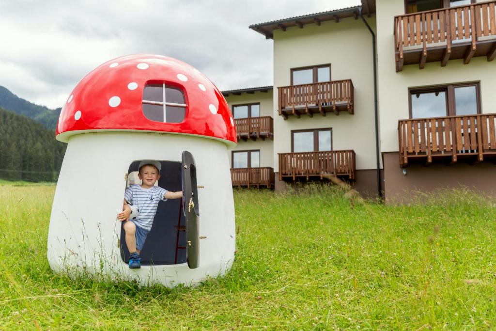 a young child is sitting in a mushroom house at Tatry Panorama in Pavčina Lehota