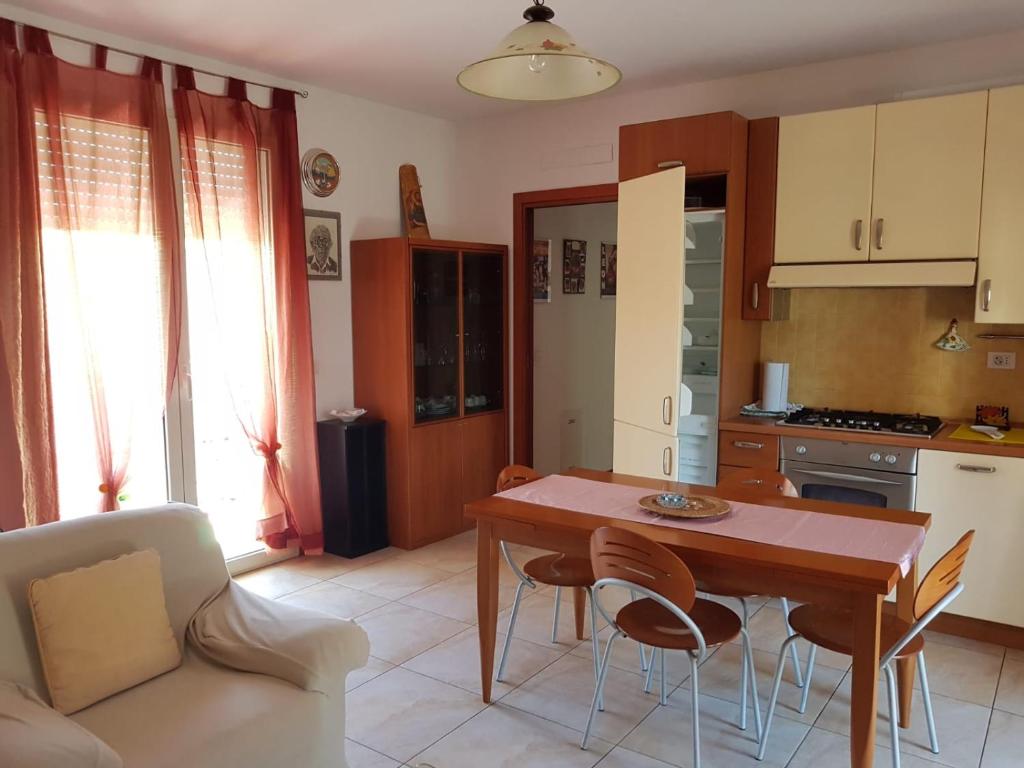 ein Wohnzimmer mit einem Tisch und Stühlen sowie eine Küche in der Unterkunft Sea House Rimini Fiera in Rimini