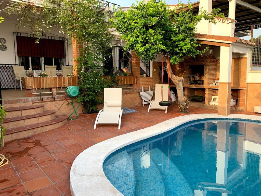 a swimming pool with white chairs next to a house at Antigua Estación de Campanillas in Málaga