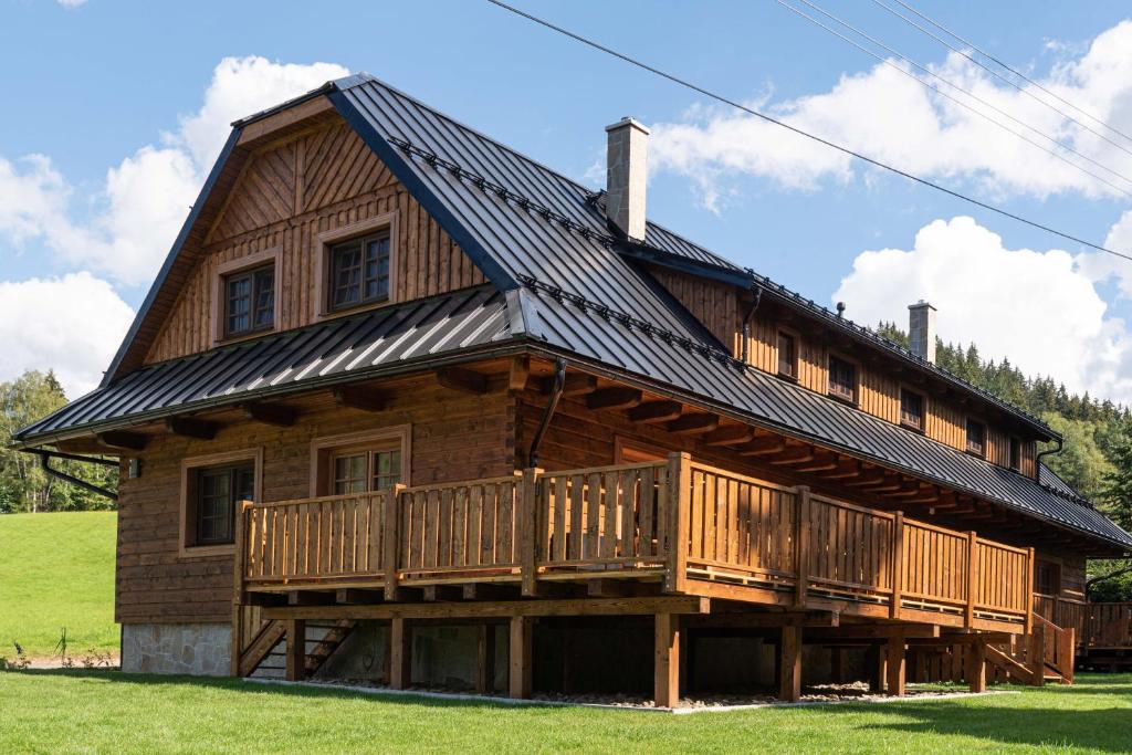 een groot houten huis met een gambrel dak bij U Justina na břehu in Velké Karlovice