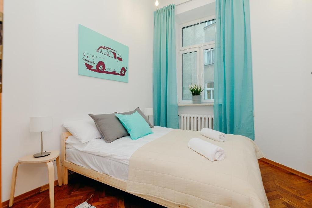 1 dormitorio con 1 cama con cortinas azules y ventana en ShortStayPoland Klonowa (B29), en Varsovia