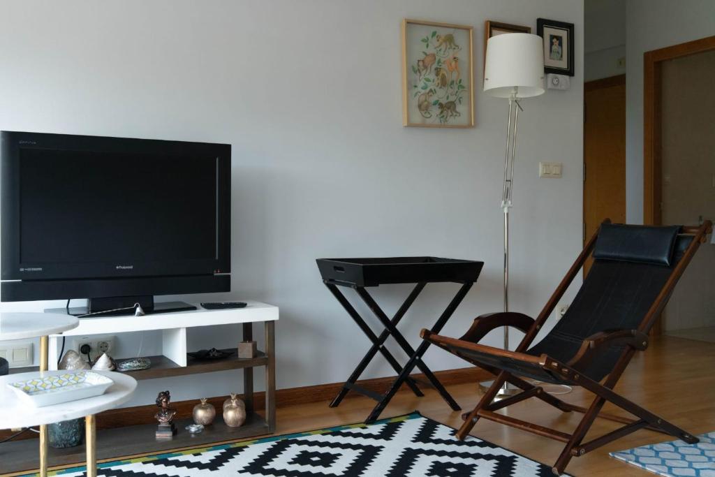 ein Wohnzimmer mit einem Stuhl und einem TV in der Unterkunft Ático con vistas al mar in A Guarda