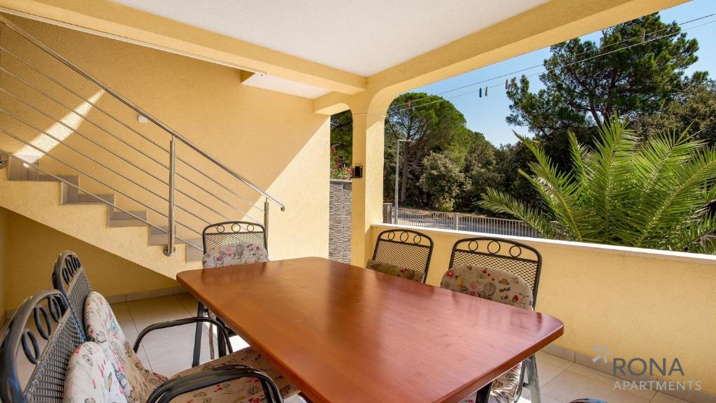 a porch with a wooden table and chairs on a balcony at Rona apartments Goran in Šimuni