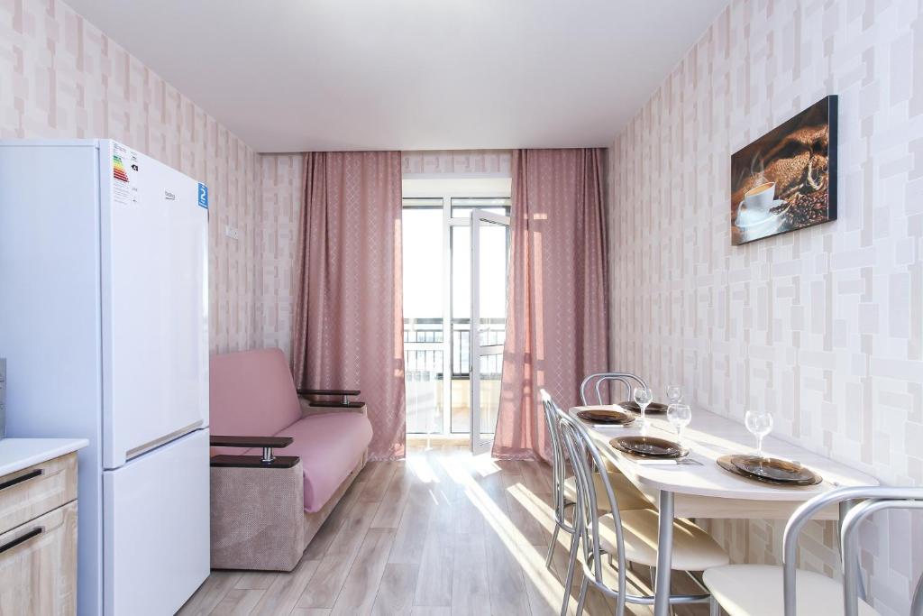 uma cozinha com uma mesa e um frigorífico branco em Современная квартира в новом ЖК Центр с парковкой em Novosibirsk