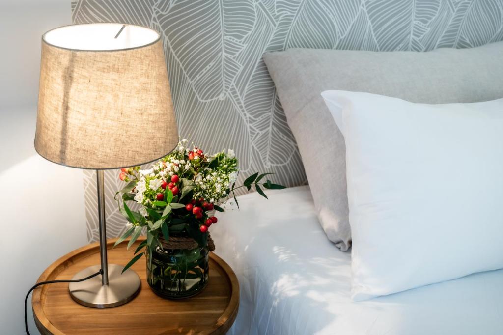 un tavolo con una lampada e un vaso di fiori su un letto di Hôtel & Séminaire Le Patio Occitan - Toulouse Ouest - La Ramée a Cugnaux