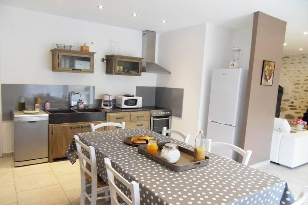 a kitchen with a table and a kitchen with a refrigerator at Le gîte du Jas Vieux in Montfort