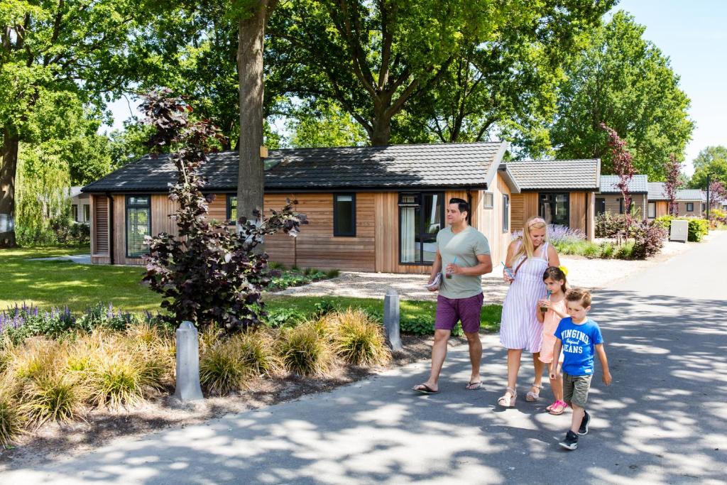 a family standing in front of a log cabin at Europarcs Zuiderzee in Biddinghuizen