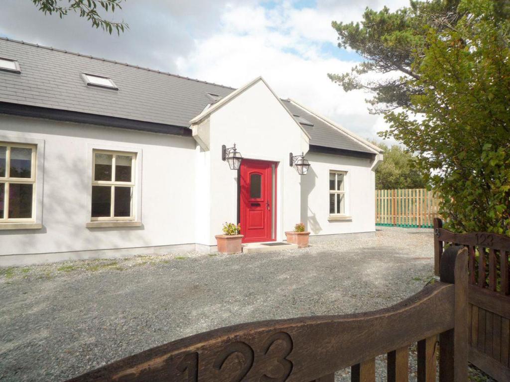 a white house with a red door at TÍ Mhaggie Holiday Cottage by Trident Holiday Homes in Gowla