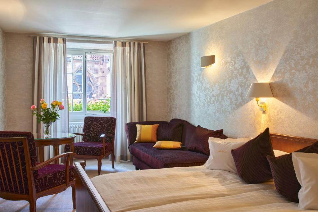 pokój hotelowy z łóżkiem i kanapą w obiekcie Boutiquehotel Oberkirch im Zentrum we Fryburgu Bryzgowijskim