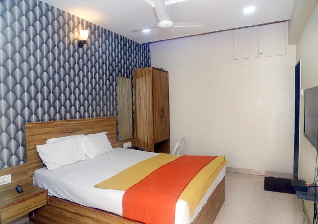 1 dormitorio con 1 cama con una manta colorida en Hotel Radhika Pune, en Pune