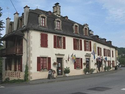 a large white building with red windows on a street at Auberge de Forgès in Forgès