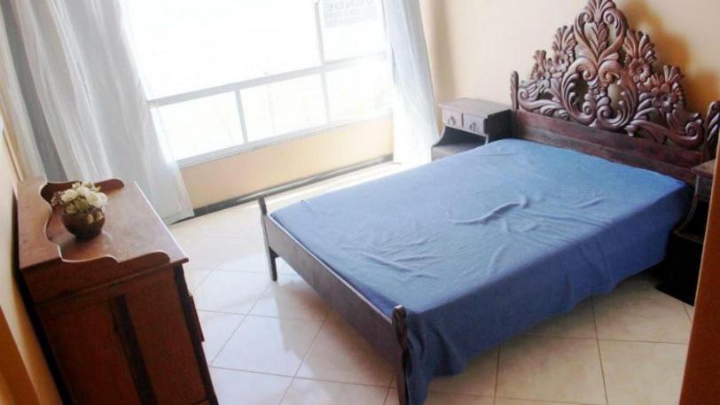 a bedroom with a blue bed with a wooden headboard at JANELA SOBRE O MAR DE GUARAPARI in Guarapari