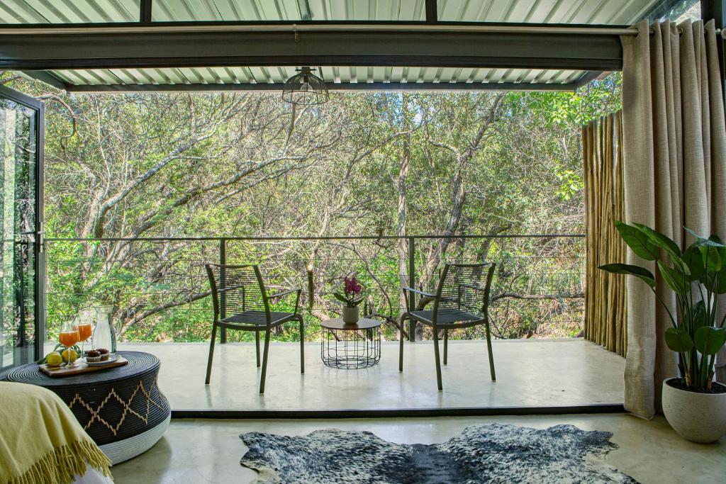 a screened in porch with two chairs and a table at Nehema Manor in Hartbeespoort