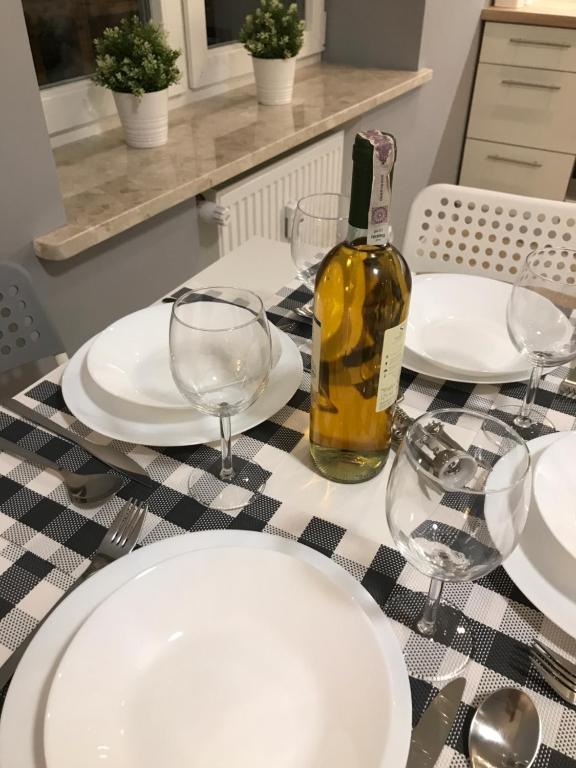 a table with white plates and a bottle of wine at Apartament BARCELONA in Białystok