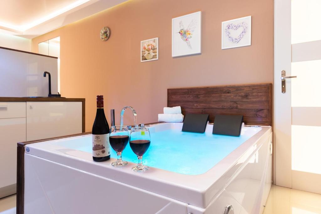 - une baignoire avec deux verres de vin dans l'établissement Lilly De Luxe Apartment with jacuzzi, à Michałowice