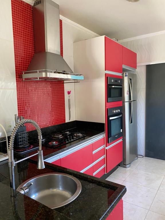 czerwona kuchnia ze zlewem i kuchenką w obiekcie Casa Rasa w mieście Búzios