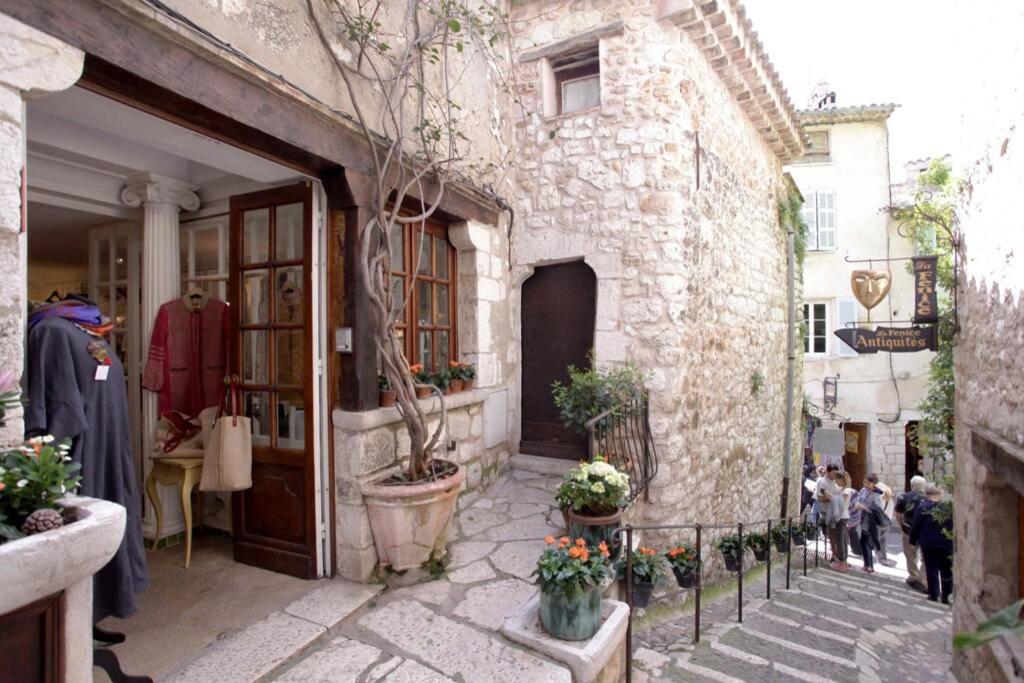 - un bâtiment en pierre avec une porte et des fleurs dans une cour dans l'établissement Maison pittorresque St Paul de Vence, à Saint-Paul-de-Vence