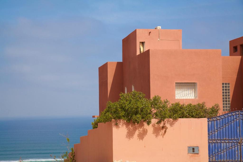 budynek na plaży z oceanem za nim w obiekcie Riad Daribis vue sur la mer Agadir w mieście Rbat