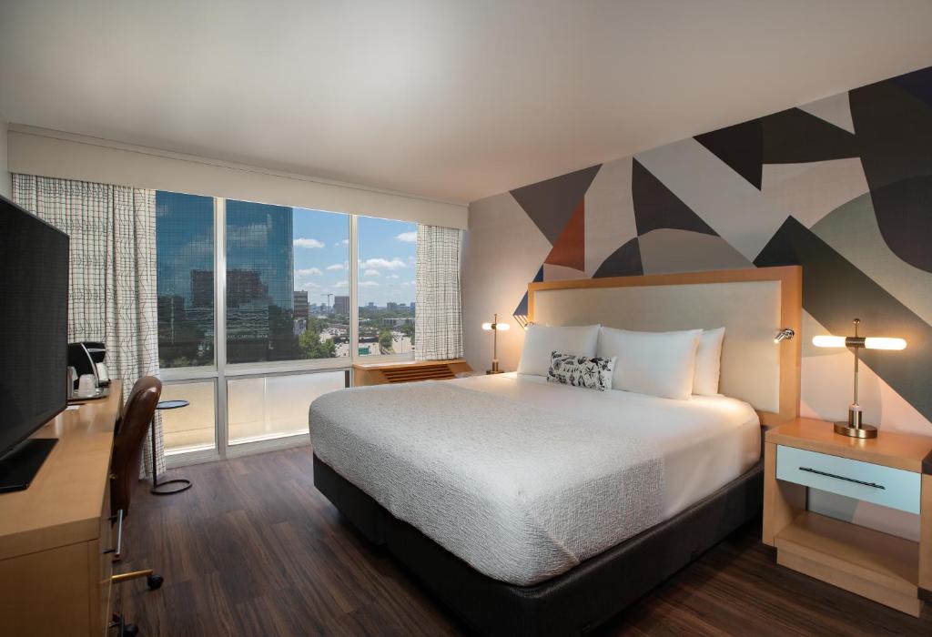 a hotel room with a bed and a large window at The Beeman Hotel in Dallas