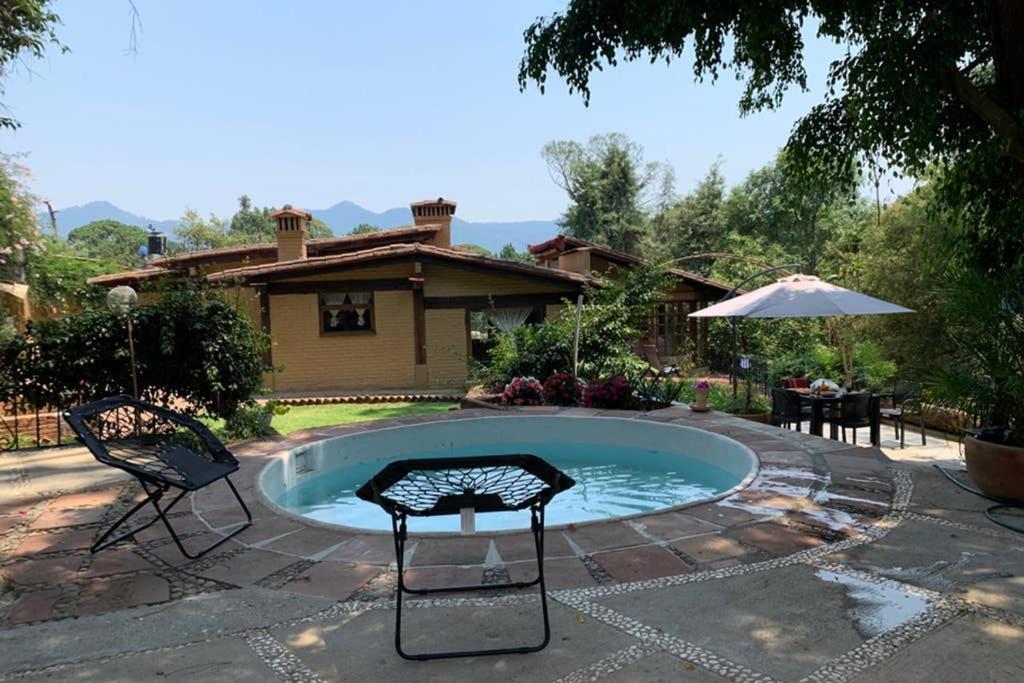 einen kleinen Pool mit zwei Stühlen und einem Sonnenschirm in der Unterkunft Casa Atardecer Valle de Bravo in Valle de Bravo