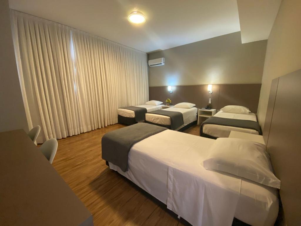 una habitación de hotel con 3 camas en una habitación en Hotel Himmelblau, en Blumenau