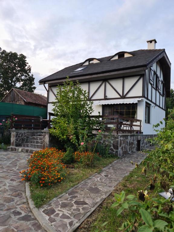 une maison blanche avec un toit noir et quelques fleurs dans l'établissement La Bunica, à Cisnădioara