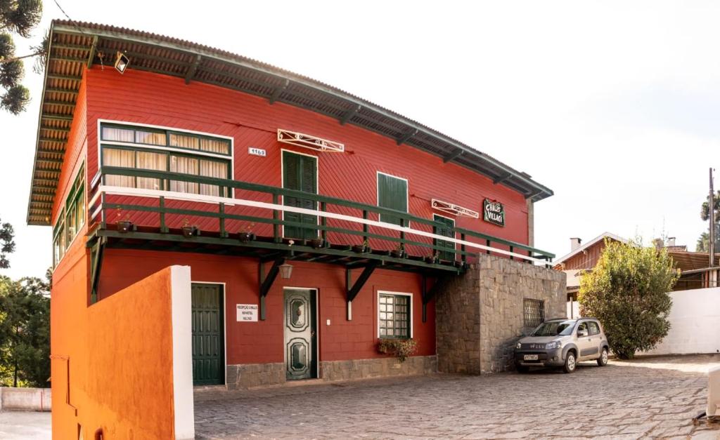 a red building with a car parked in front of it at Chalés Vill'Agi in Campos do Jordão