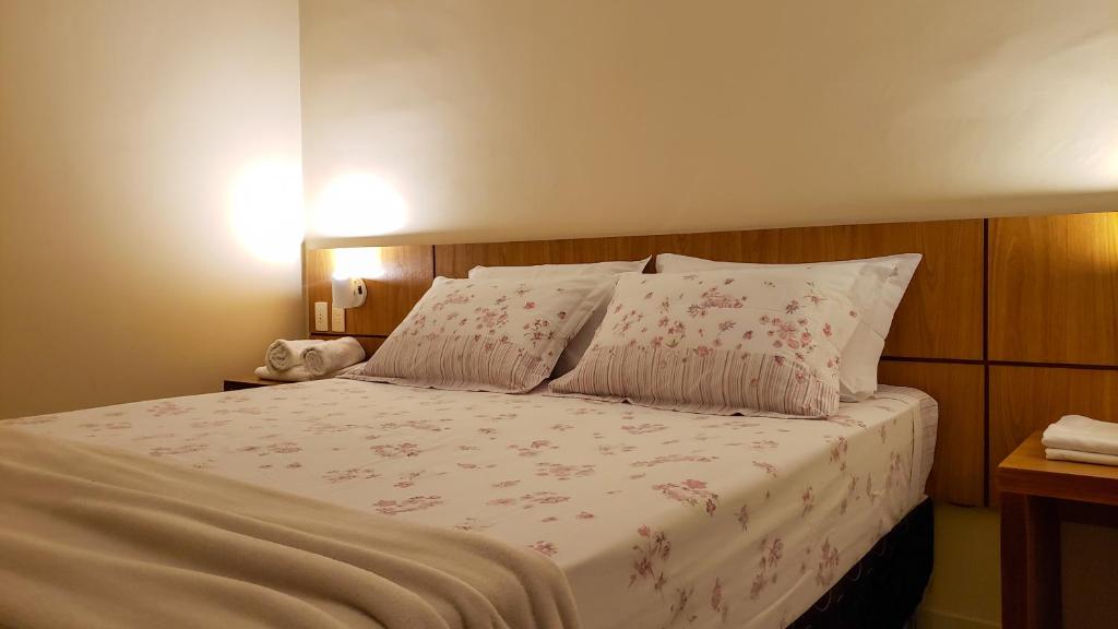 a bed with white sheets and pink flowers on it at Vilamar Suítes in Aquiraz