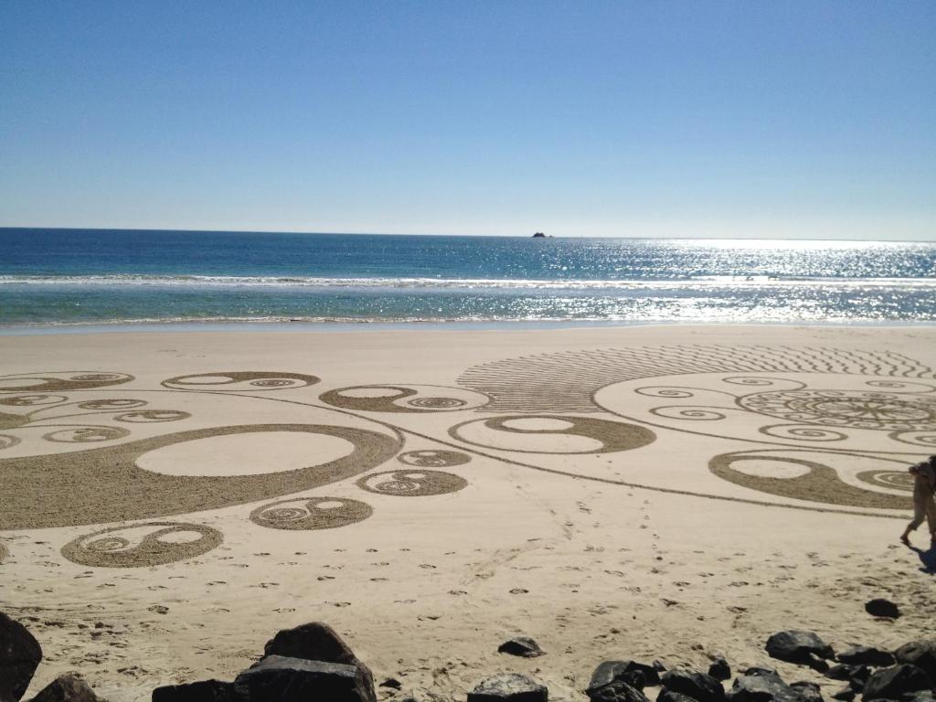 a drawing in the sand on a beach at Aqua Soleil - Byron Bay Apartment For Rent in Byron Bay