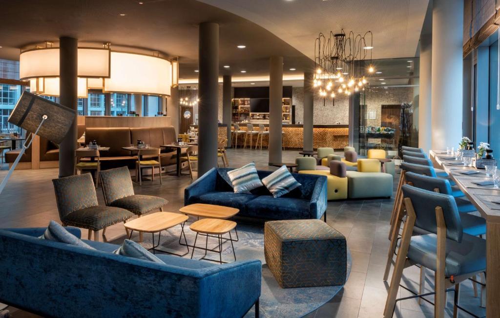 a lobby with couches and tables and a restaurant at Hyatt House Frankfurt Eschborn in Eschborn