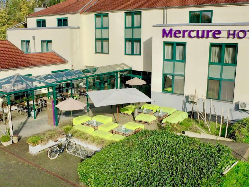 クレーフェルトにあるMercure Tagungs- & Landhotel Krefeldのテーブルと傘が備わるホテルの空中ビュー