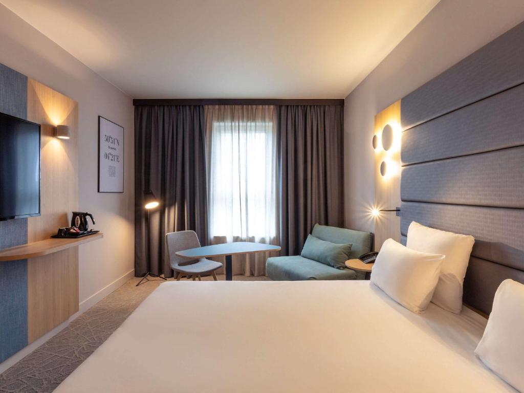 a hotel room with a bed and a chair and a table at Novotel Brussels Centre Midi in Brussels