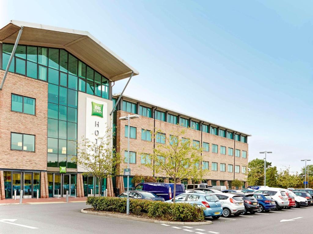 a large building with cars parked in a parking lot at ibis Styles Birmingham NEC & Airport in Bickenhill